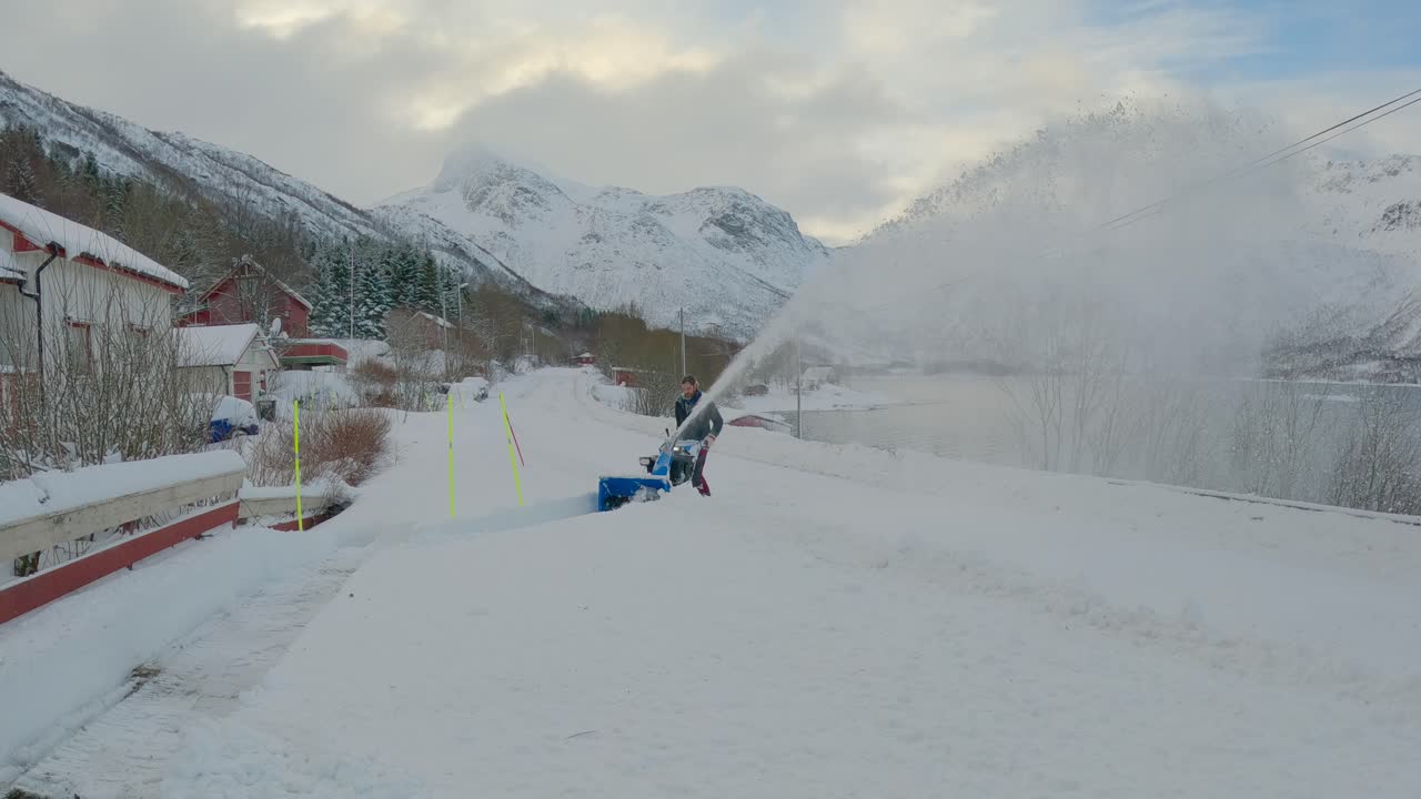 Dopo una forte nevicata, un uomo sgombra la neve con uno spazzaneve vicino alla strada, ripresa fissa