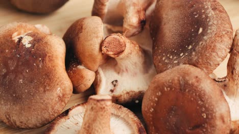 pile of fresh shiitake mushrooms on wooden cutting board