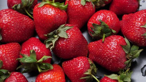 una gran cantidad de fresas rojas y maduras girando, en primer plano