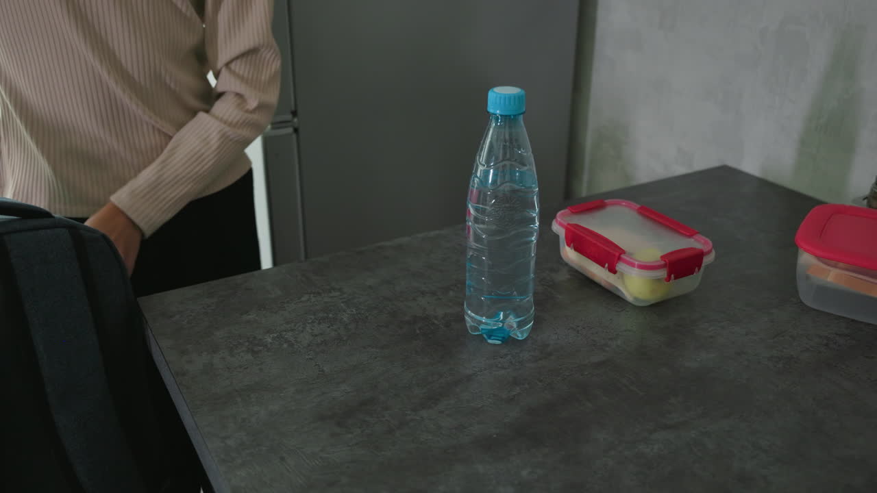 girl and boy in casual wear smiling faces packing backpacks in bright kitchen with books notebooks lunchboxes water bottles preparing for school day commute with sibling in daily morning routine