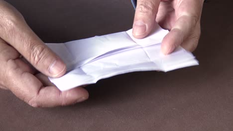 a gemstone collector opens a parcel paper and examines a cut stone, close up