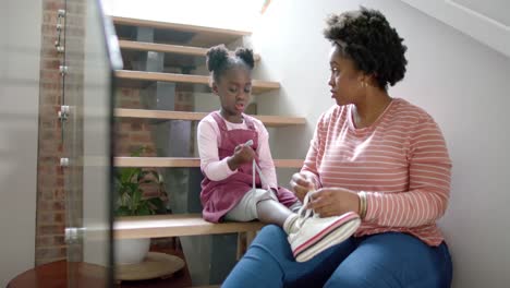 Madre-Afroamericana-Aconsejando-Y-Atando-Zapatos-De-Hija-En-Casa,-Cámara-Lenta