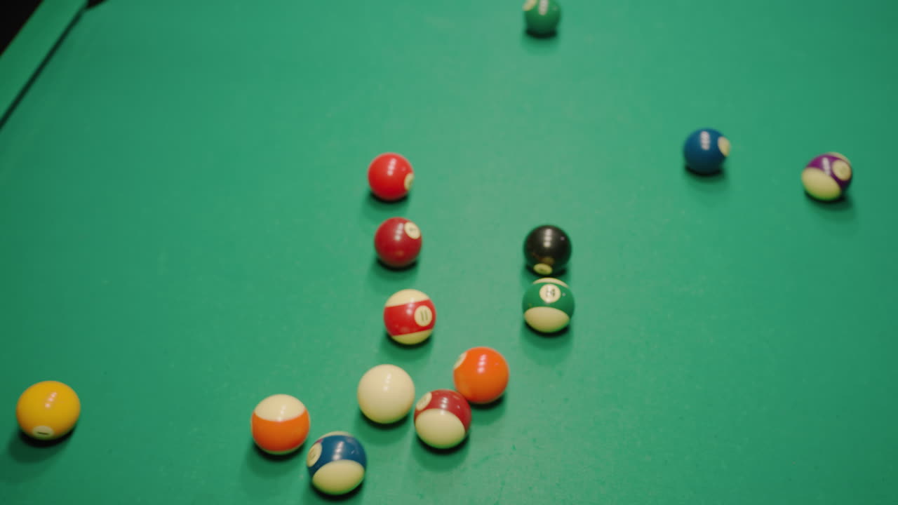 las bolas de billar explotan desde la formación triangular en la mesa de billar verde después de un poderoso tiro de ruptura, rodando en múltiples direcciones con un fuerte impacto, creando movimiento dinámico y acción de ritmo rápido