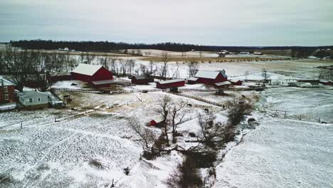 un dron aéreo captura graneros rodeados de un vasto paisaje agrícola cubierto de nieve.