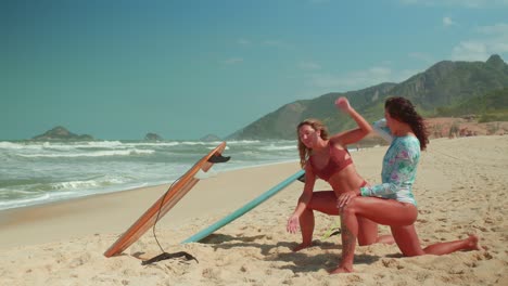 Two women stretching on a tropical beach with surfboards