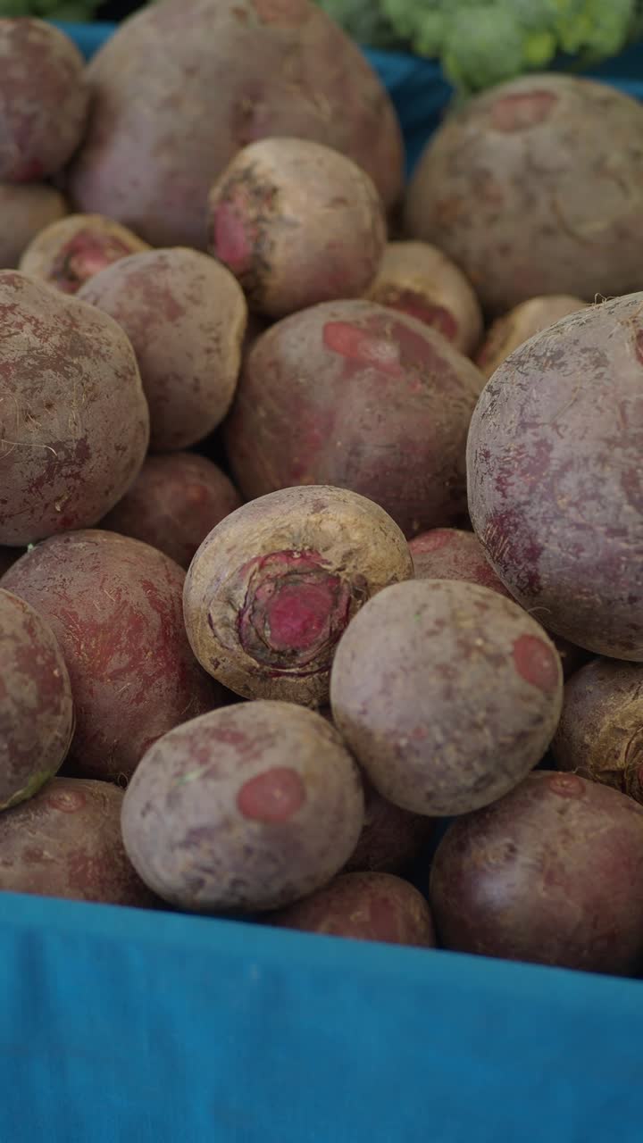 Barbabietole fresche in un contenitore blu a un mercato contadino.