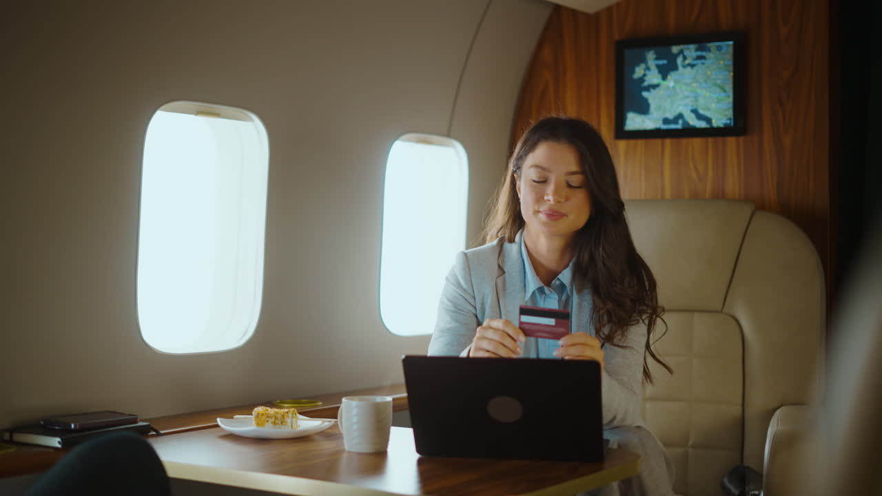 Businesswoman using laptop and credit card on private jet