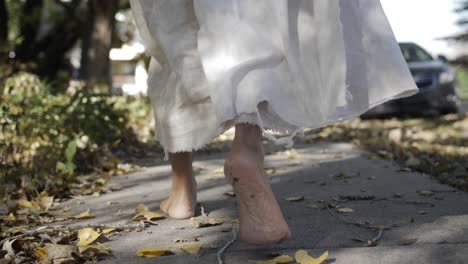 a dramatic slow motion closeup of jesus' feet walking down a sidewalk while he wears a white, tattered robe