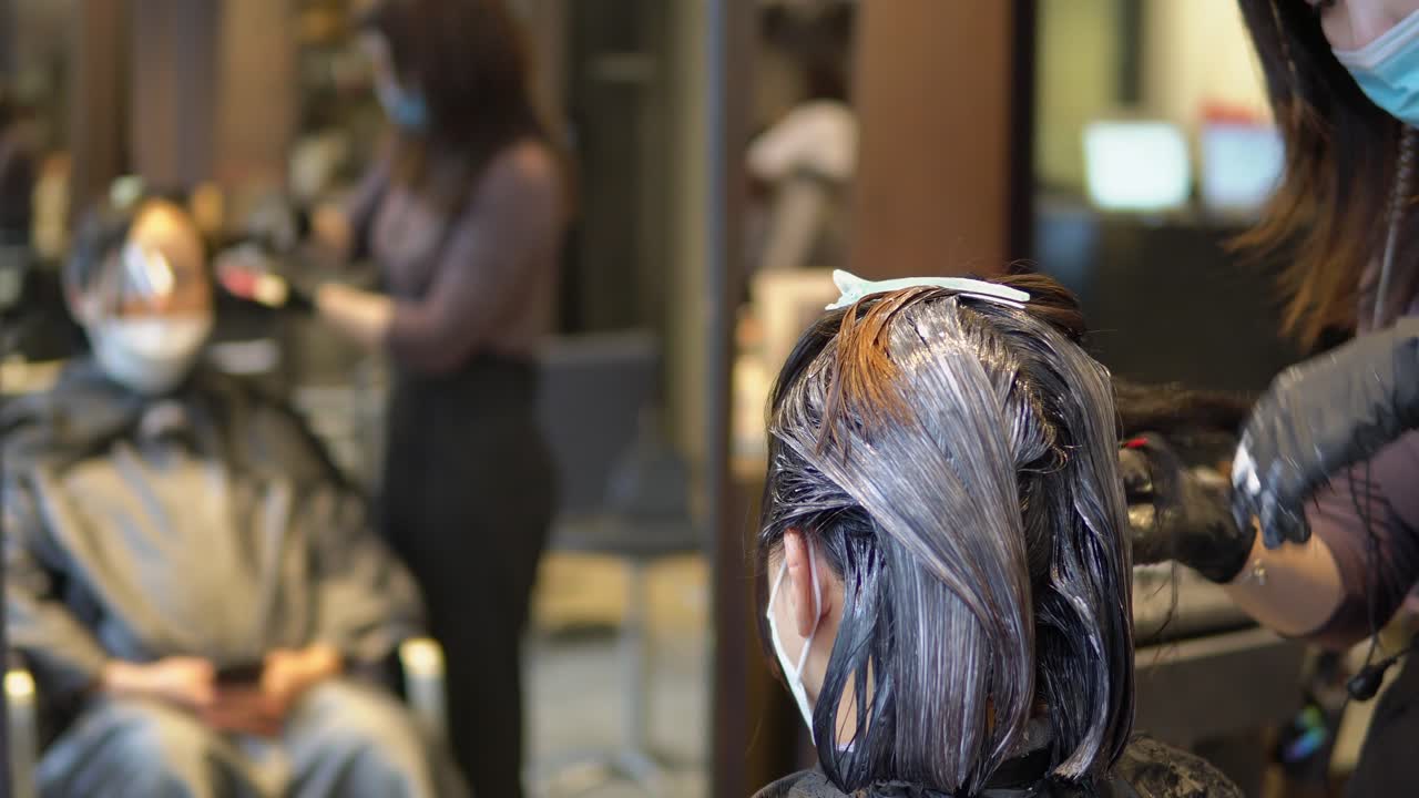 얼굴 마스크를 쓴 스타일리스트가 머리에 색을 칠한 브루네트 여성의 머리, covid-19 전염병