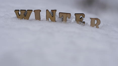 Winter-intro-title,-wooden-letters-in-snow,-focus-shift