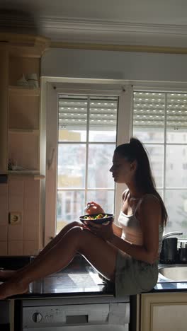 mujer comiendo ensalada junto a la ventana