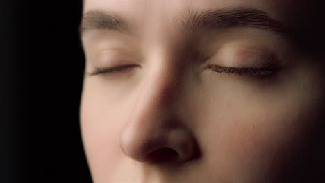 Macro-of-female-face-beauty-resting-with-closed-eyes-in-black-studio.Tired-woman