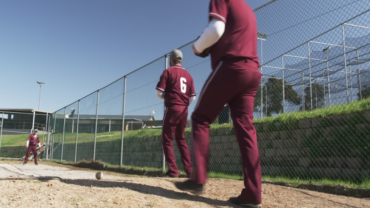 Uomo in uniforme che cammina sul campo da baseball, tenendo guanto e palla.