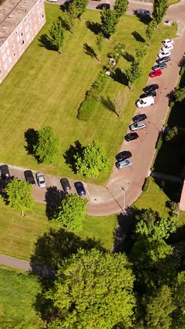 aerial view of a suburban neighborhood with parked cars, green spaces, and buildings