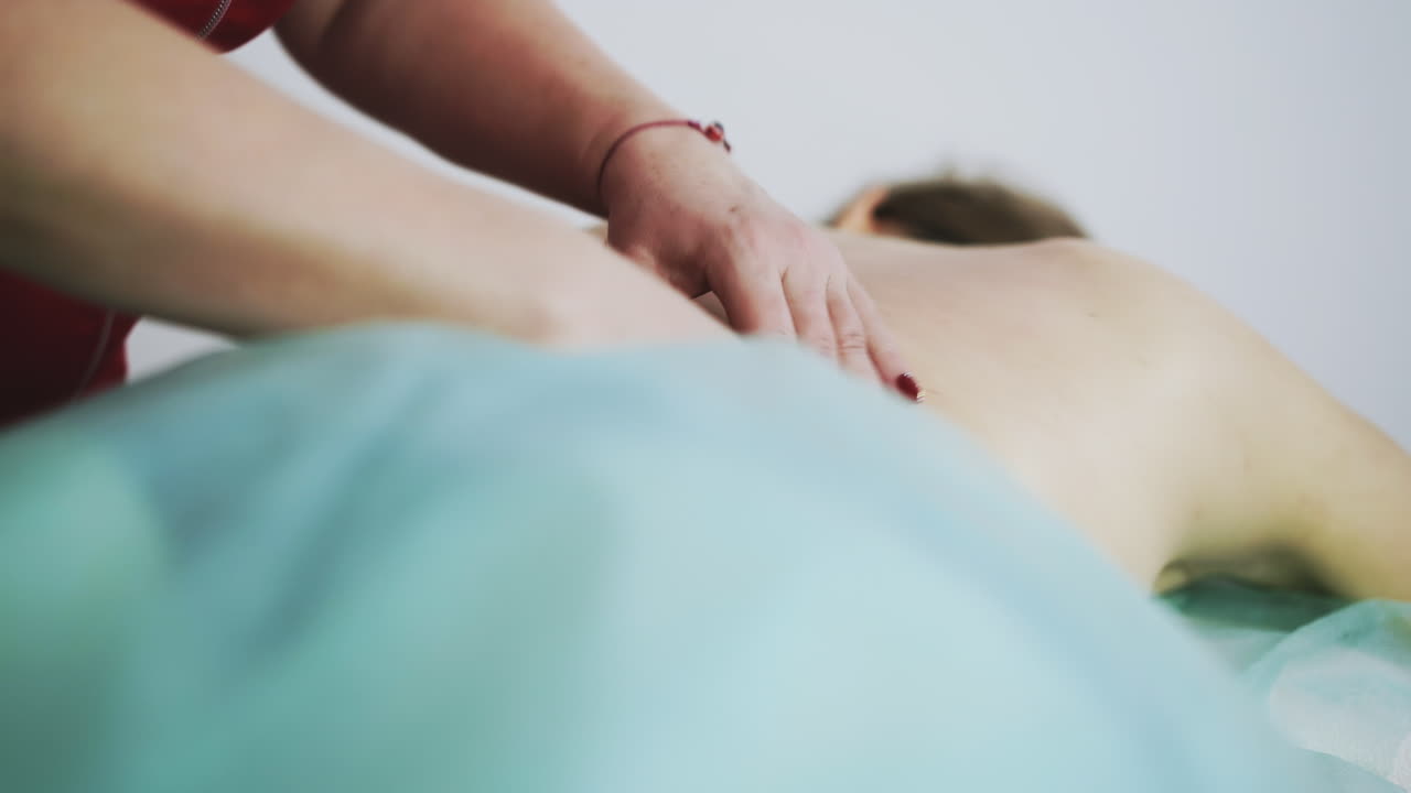 el terapeuta hace masajes a una mujer joven con dolor en la espalda baja.