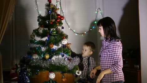 boy helping his mom. little boy helping his mom to decorate christmas tree