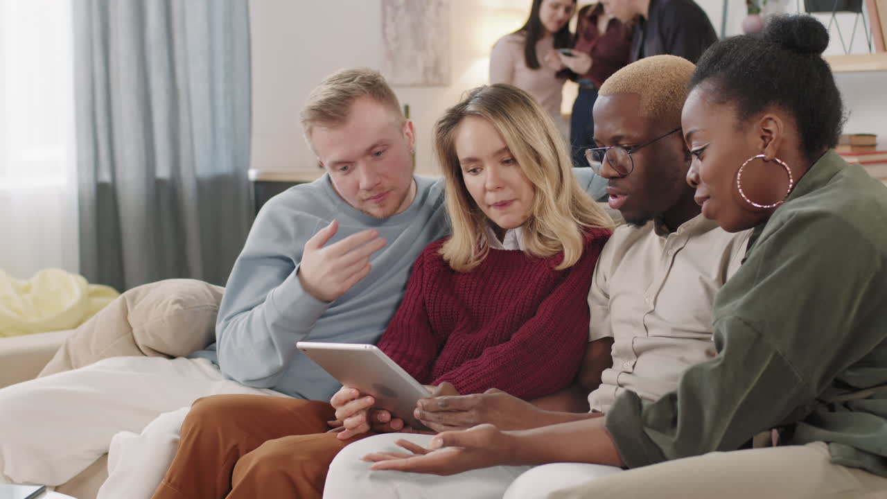 Young People Looking at Tablet and Talking in Apartment