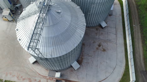metal grain elevator for storage crop. modern silo. large aluminum container. orbital video. aerial top view.