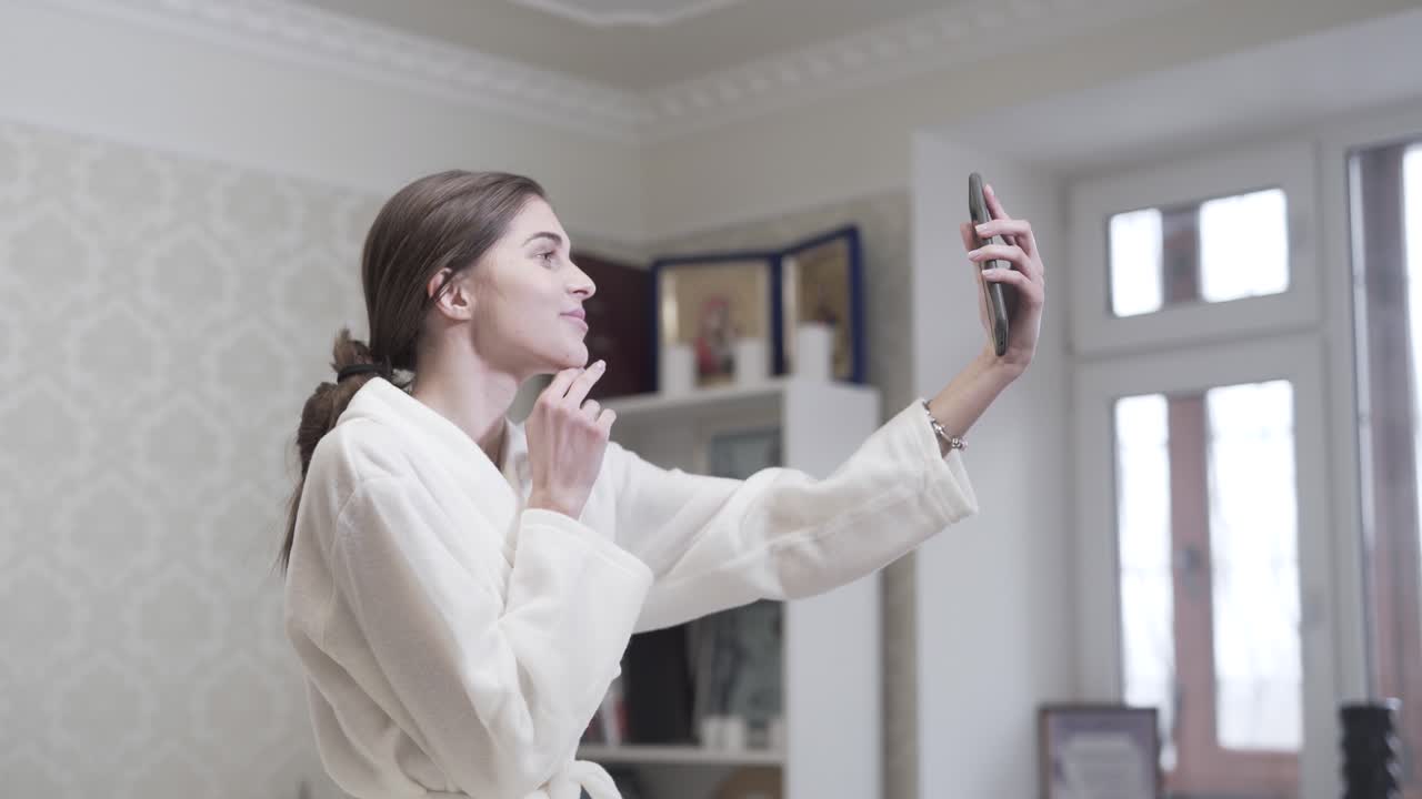 mujer sonriendo para una selfie mientras usa una bata en el spa