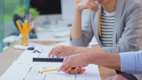 male and female architects working in office together at desk on plans for new building