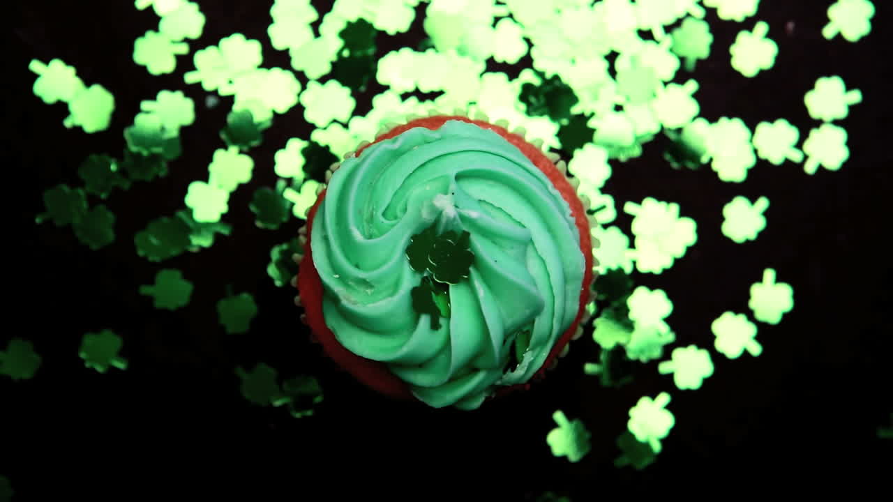 st. patrick's day cupcake girando con confeti de trébol verde que está cayendo
