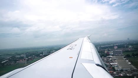 shot of an airplane wing taken from inside the plane while the plane is flying close to the ground