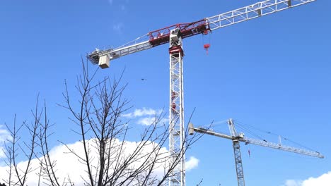 Ein-Paar-Hohe-Stahlbaukräne-Isoliert-Auf-Blauem-Himmel,-Bewegungsansicht