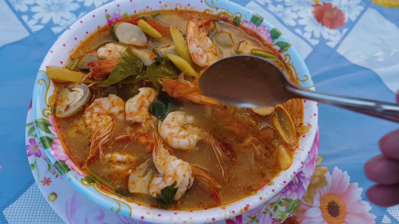 persona probando la deliciosa sopa tom yam kung con una cuchara