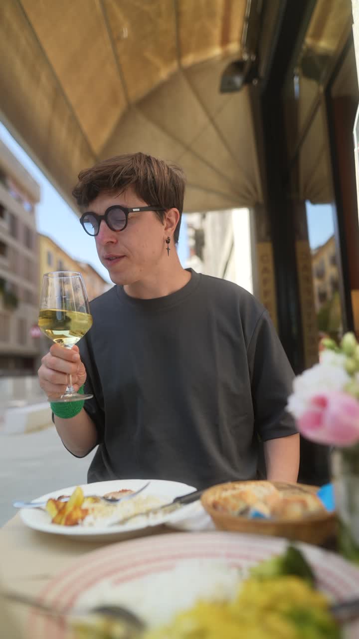 Person enjoying a meal and wine outdoors at a cafe.