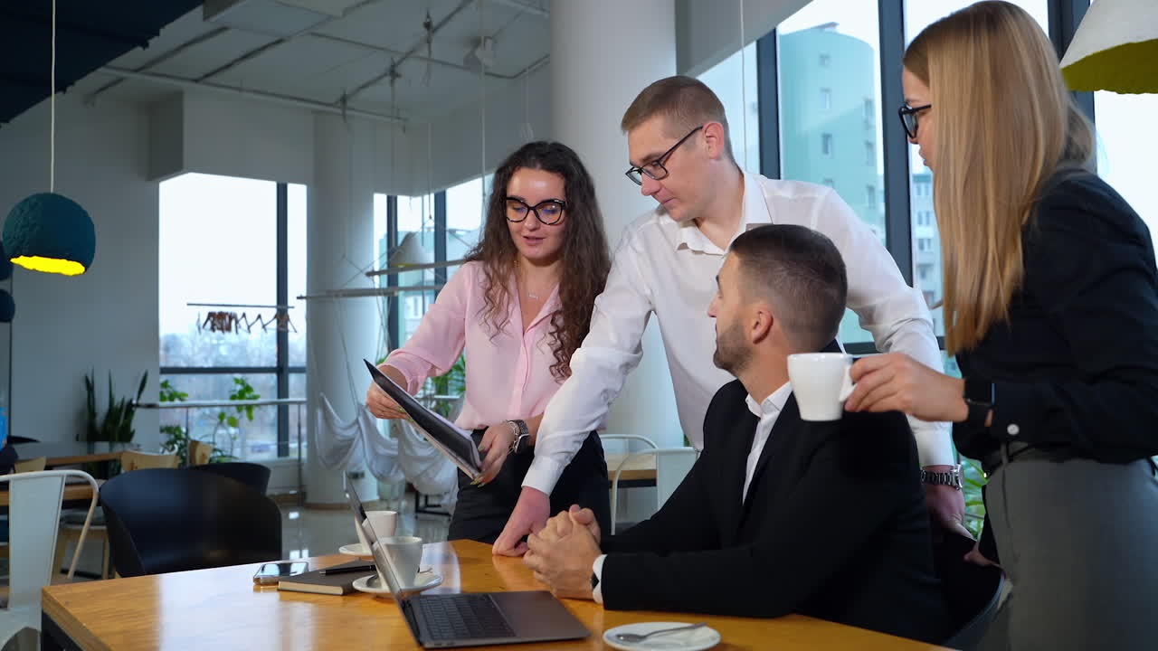 Young productive team discussing the project in the office. Dark-haired female employee suggesting idea, showing chart. Light office backdrop.