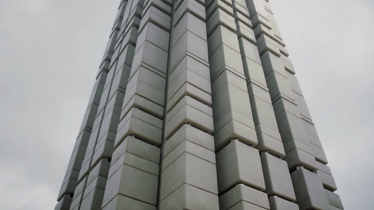La telecamera si inclina verso l'alto e arretra, rivelando una torre modulare impilata con giunzioni, per l'architettura.