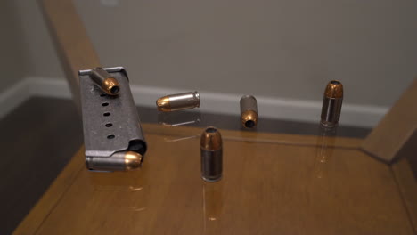 Handgun-magazine-with-hollow-point-bullets-scattered-around-it-on-glass-table