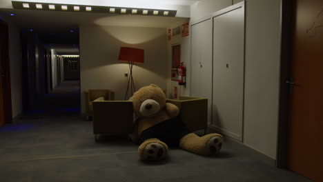 giant teddy bear in hotel corridor at night