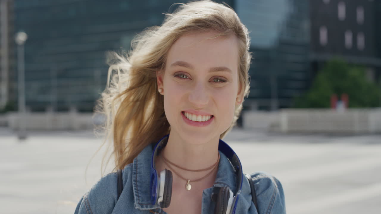 초상화 아름다운 젊은 금발 여성 학생이 도시에서 웃으며 독립적인 도시 생활 방식을 즐기고 바람에  ⁇ 는 머리카락 느린 동작