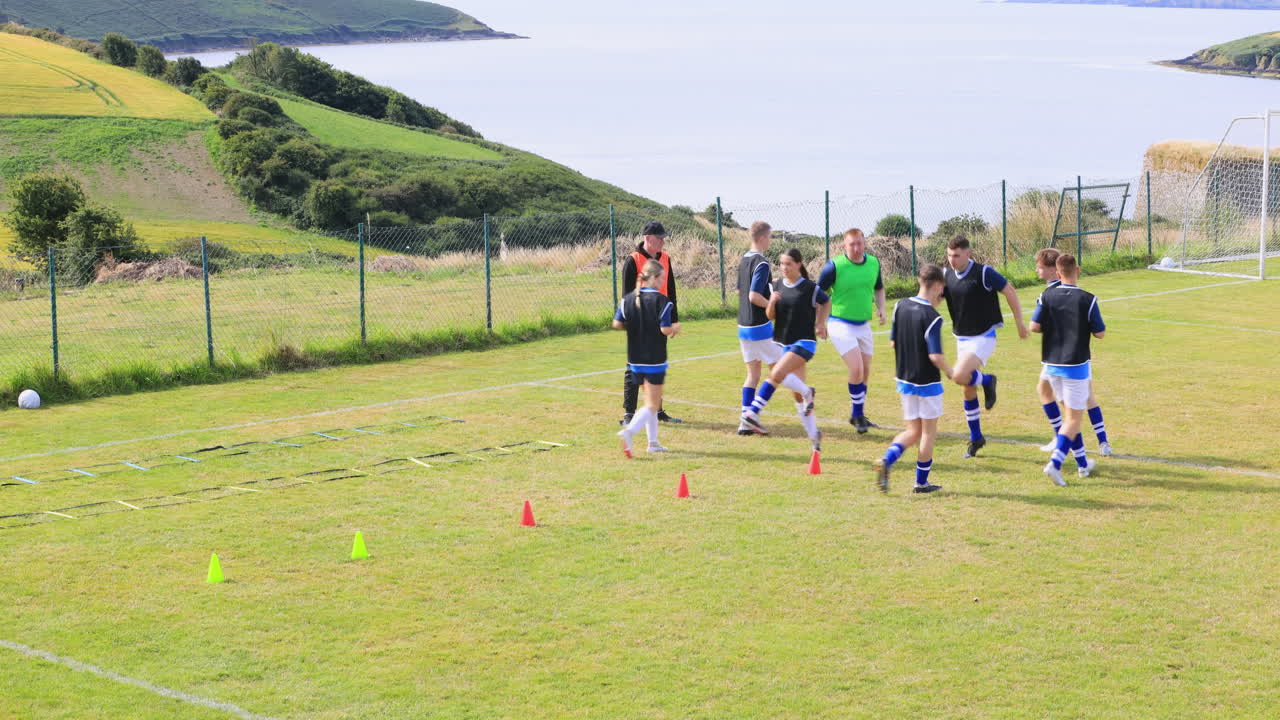 Male and female soccer players warming up and coach on pitch