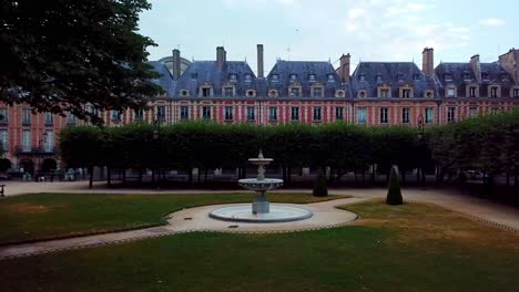 View-of-fountain-and-linden-trees-in-front-of-red-facade-houses-at-Place-des-Vosges