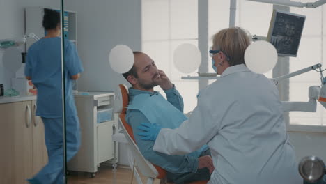 paciente con dolor de dientes explicando el dolor al dentista en la clínica de atención bucal