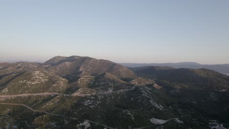 drone-video-over-the-Opuzen-area-in-Croatia,-recording-the-mountain-range-at-sunset-on-highway-8,-car-traffic-can-be-seen-in-the-distance