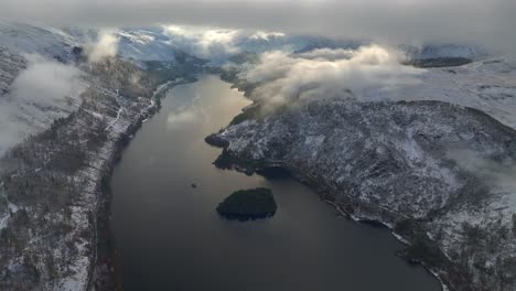 lago en el paisaje rural de invierno con vuelo justo por debajo del nivel de nubes bajas hacia el extremo del valle nublado brillante