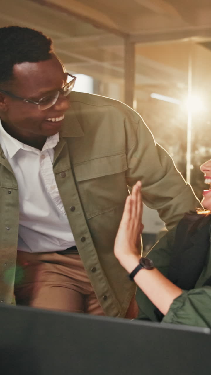 Happy Coworkers High-Fiving and Laughing While Working on Laptop