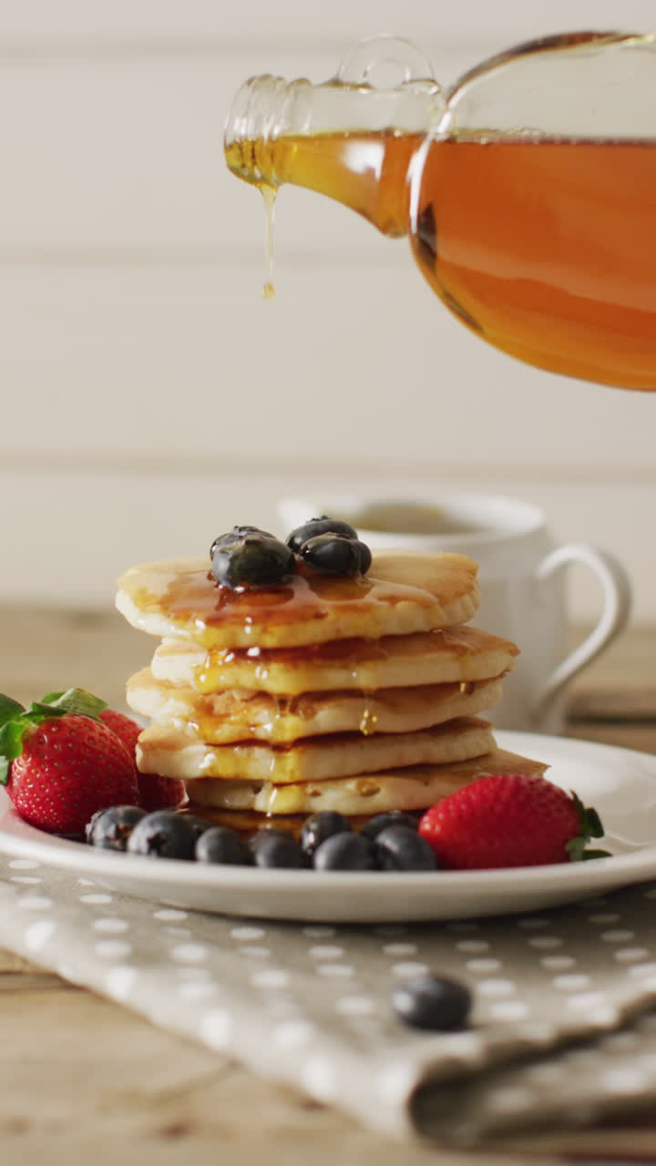 video vertical de jarabe de arce que se vierte en panqueques con frutas