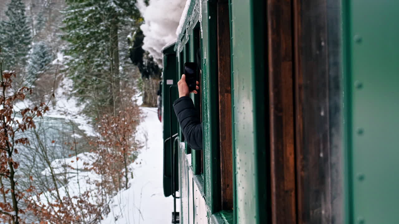 Näkymä liikkuvasta Mocănița-höyryjunasta sen sisältä, paljas metsä talvella, lunta, matkustajien kuvausta, Romania