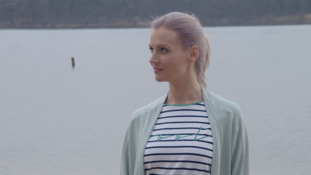 카메라를 보고 해변에 서 있는 아름 다운 여자까지 기울이기