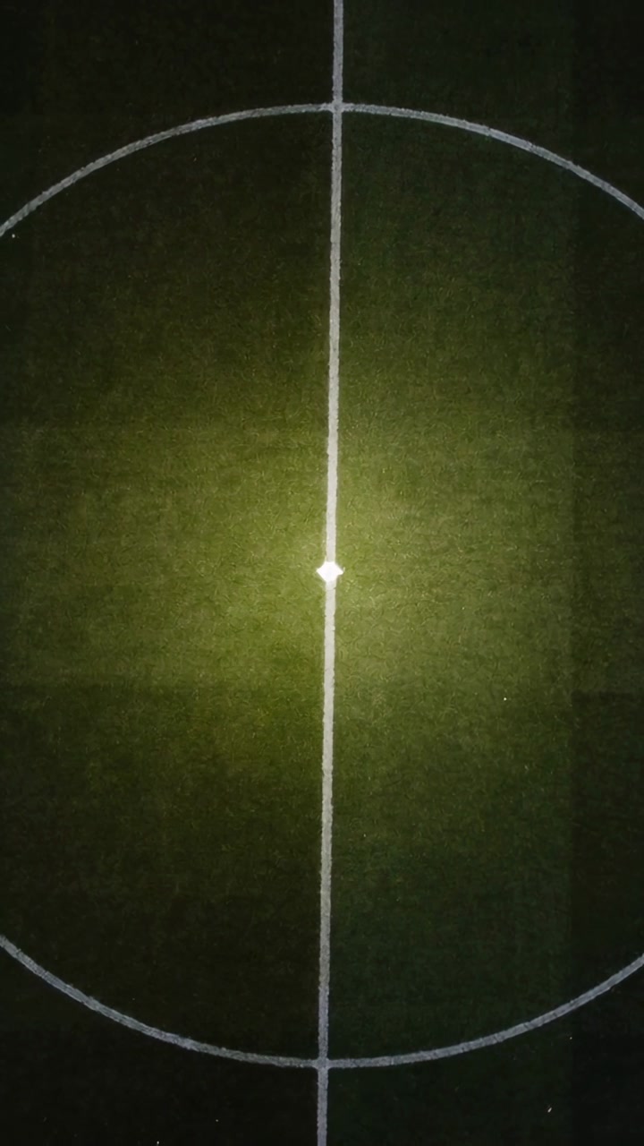 Vertical video: Circle and midline pulsing under moving beam on turf at night showing center mark