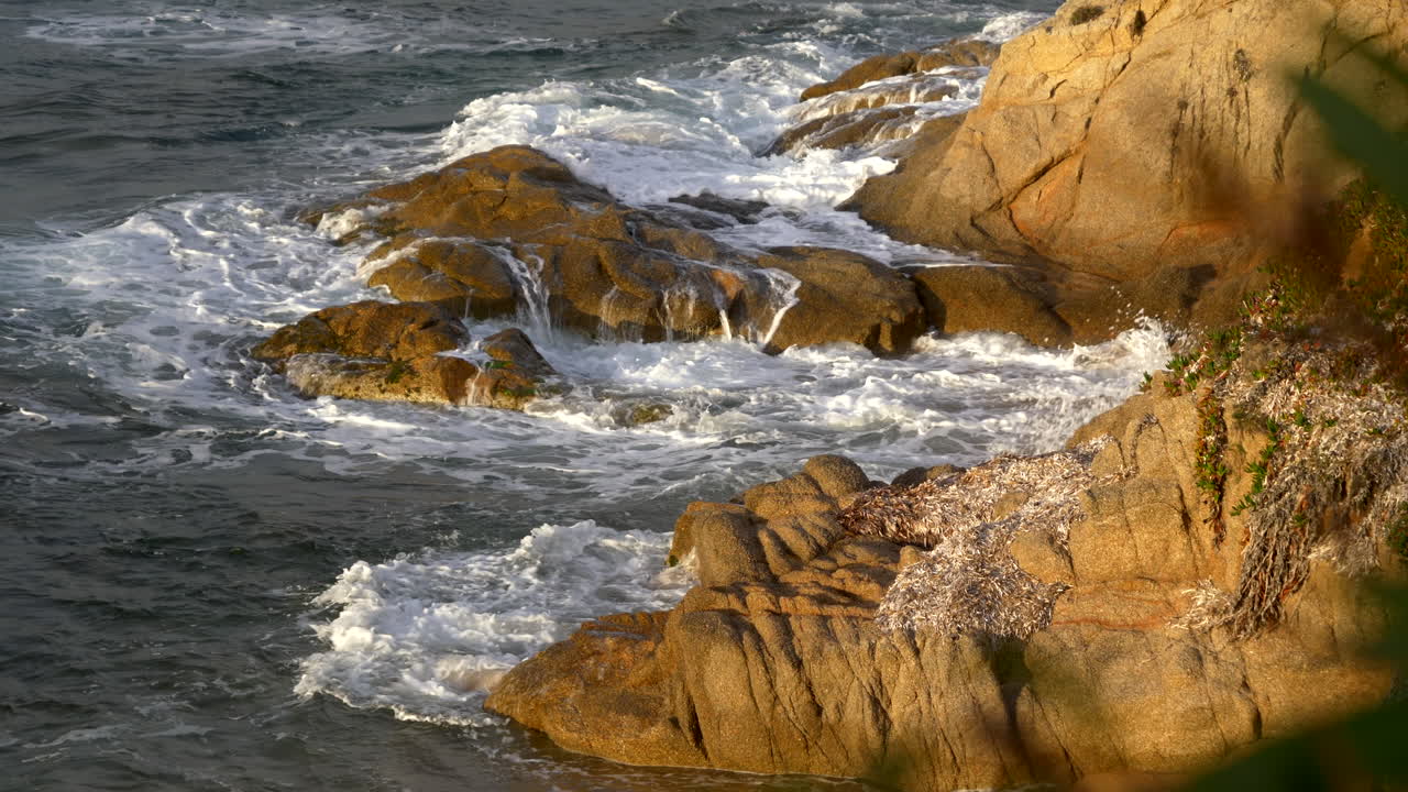 Onde del mare che si infrangono sulle rocce durante il tramonto