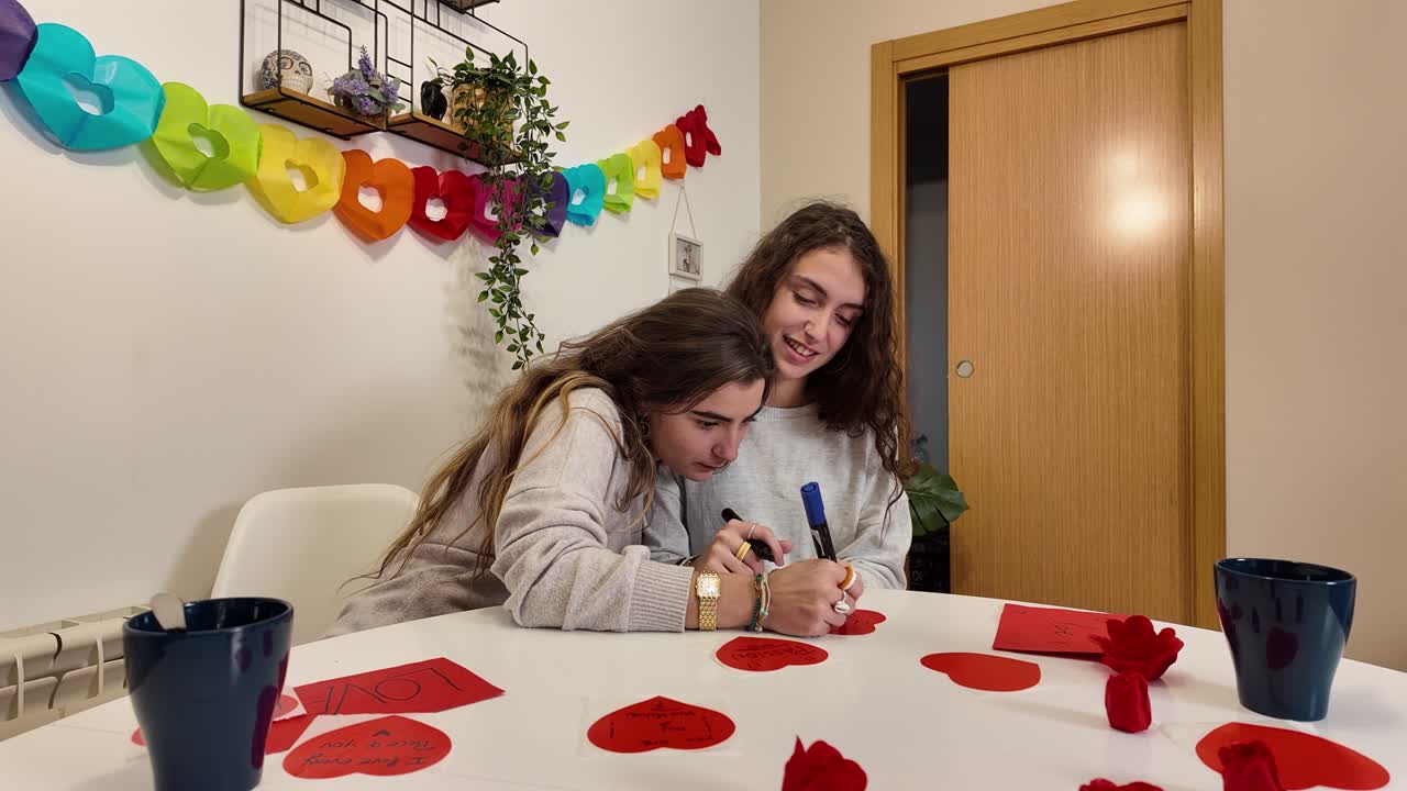 Two women making valentines day cards at a table