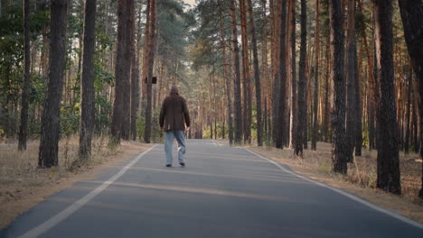 drunk homeless man walks on the road in the park