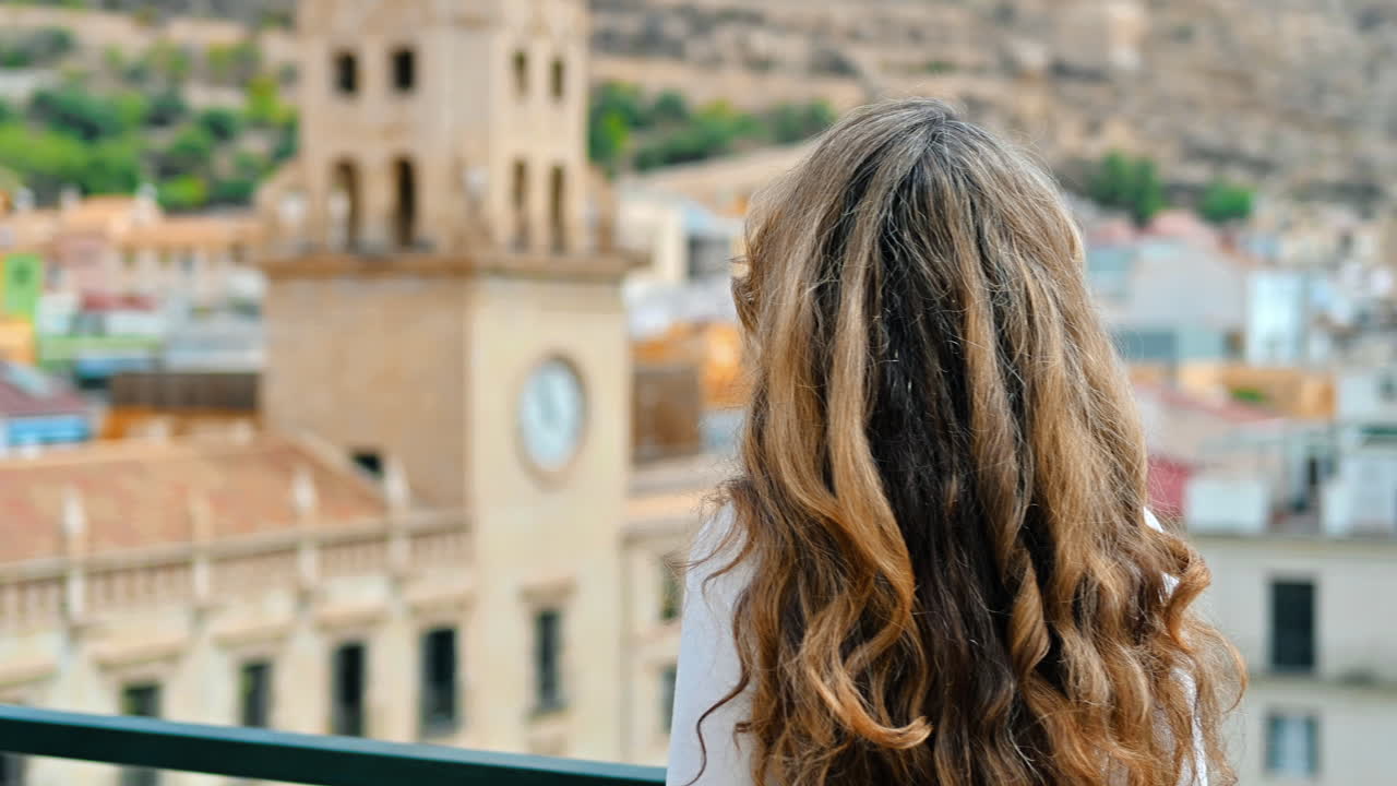 Kavkazská žena sleduje panoramatický výhled na město Alicante ve Španělsku. Radnice v pozadí