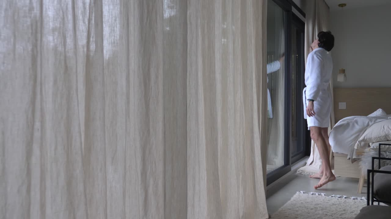 el hombre en túnica abrió las cortinas después de despertarse por la mañana