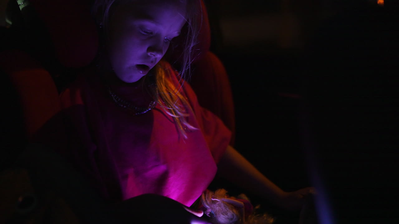 Giovane ragazza che gioca con il tablet in macchina di notte